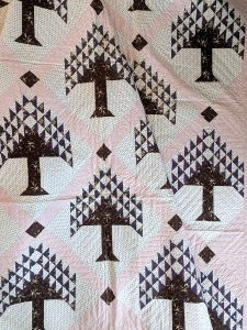Antique quilt with a tree of life block pattern in chocolate brown and navy prints with soft pink sashing.