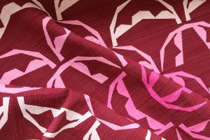 Detailed image of a modern foundation paper pieced quilt in deep red, and many shades of pink showing 1/4" spaced straight line quilting in a variegated thread.
